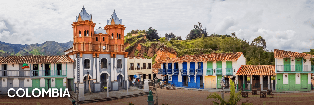 an orange and grey church next to houses in Colombia